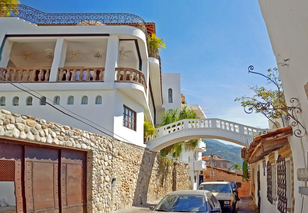 Puente peatonal blanco entre casas en una calle empedrada de Puerto Vallarta